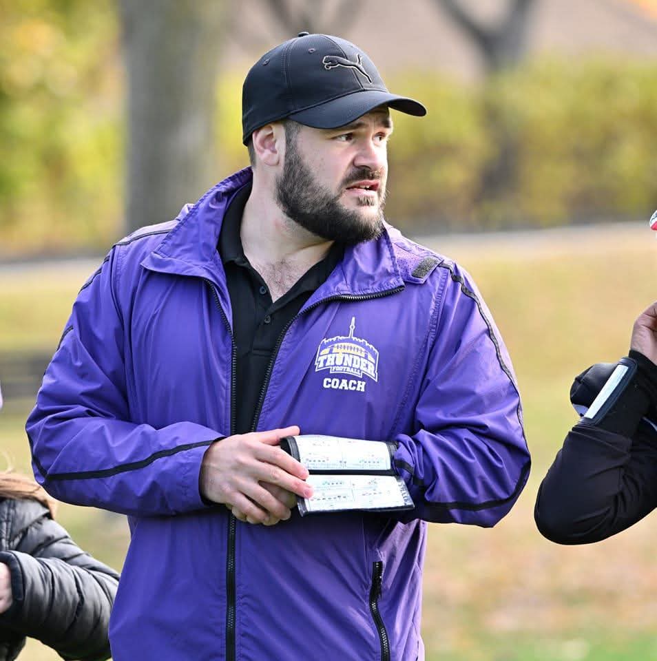 Daniel Cubellis coaching youth football, playbook in hand